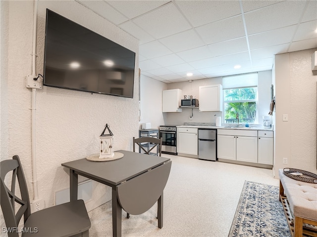 kitchen with a paneled ceiling, white cabinetry, sink, and appliances with stainless steel finishes