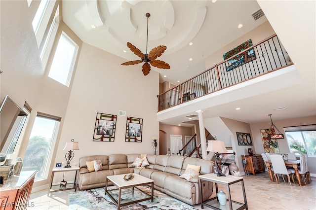 living room featuring a high ceiling, ceiling fan with notable chandelier, and decorative columns