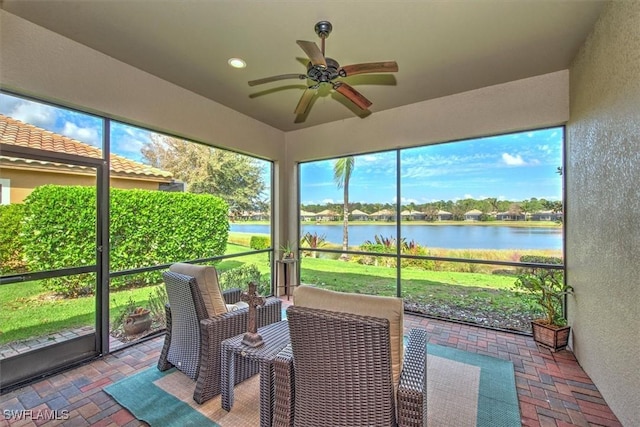 sunroom with ceiling fan and a water view