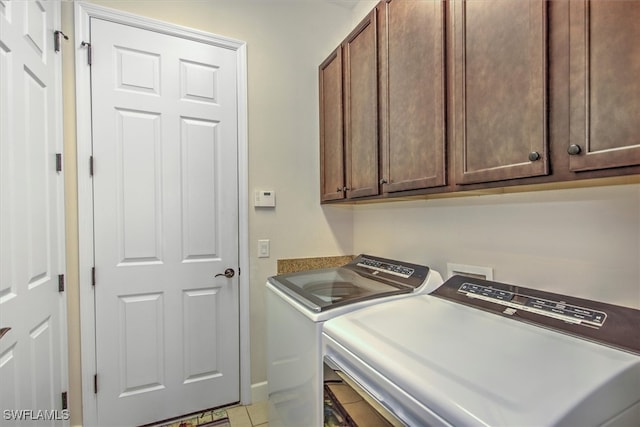 laundry area with washer and clothes dryer, light tile patterned floors, and cabinets