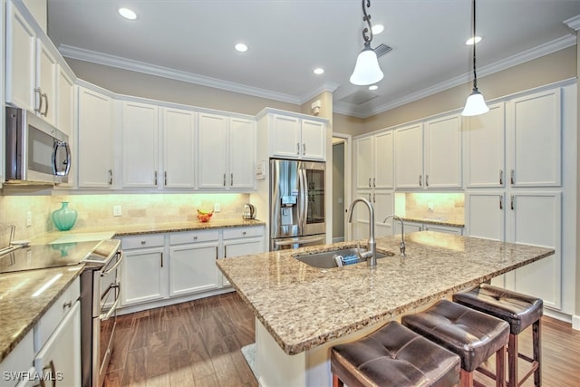 kitchen featuring appliances with stainless steel finishes, hanging light fixtures, sink, white cabinets, and backsplash