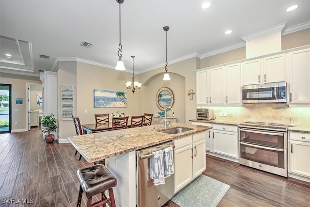 kitchen with sink, stainless steel appliances, light stone counters, and an island with sink