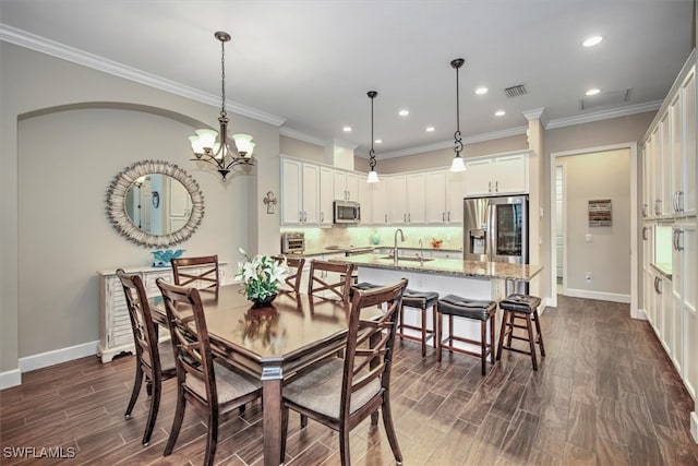 dining space with sink, dark hardwood / wood-style flooring, crown molding, and a chandelier