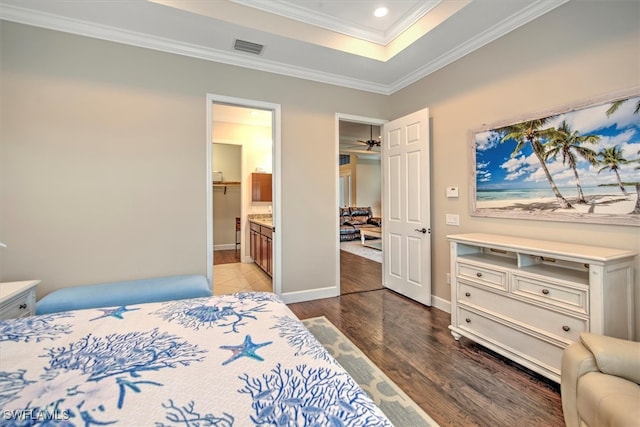 bedroom with a closet, dark hardwood / wood-style flooring, a spacious closet, ornamental molding, and connected bathroom