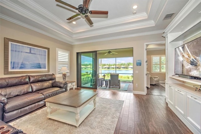 living room featuring ceiling fan, dark hardwood / wood-style floors, a raised ceiling, and crown molding