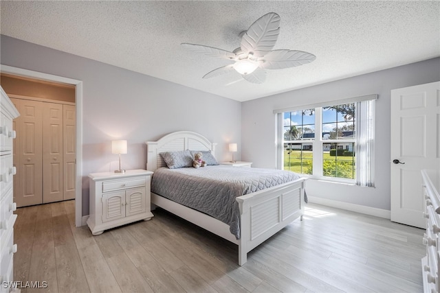 bedroom featuring light wood finished floors, baseboards, and a textured ceiling