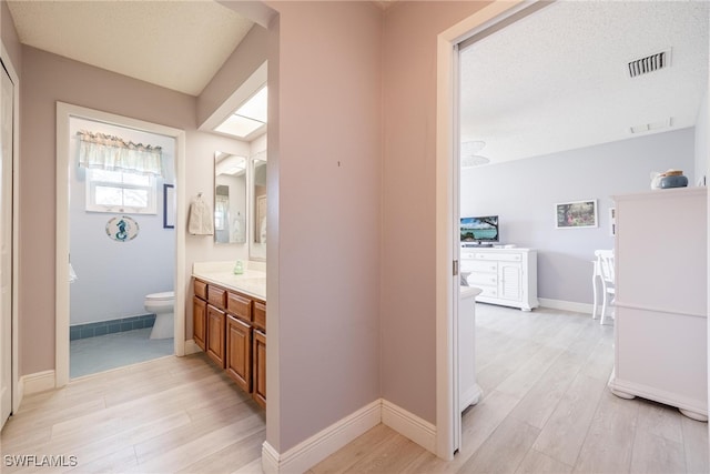 full bath featuring baseboards, visible vents, toilet, wood finished floors, and vanity