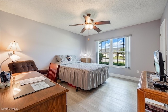 bedroom with a ceiling fan, baseboards, a textured ceiling, and light wood finished floors