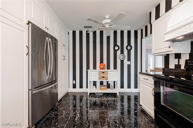 kitchen featuring dark countertops, black electric range oven, freestanding refrigerator, white cabinets, and wallpapered walls