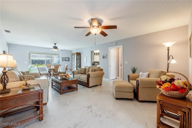 living room with marble finish floor, a ceiling fan, visible vents, and a textured ceiling