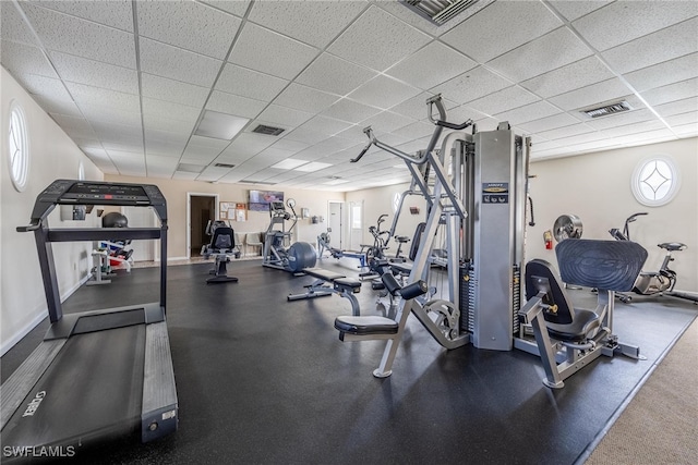 gym with a paneled ceiling, visible vents, and baseboards