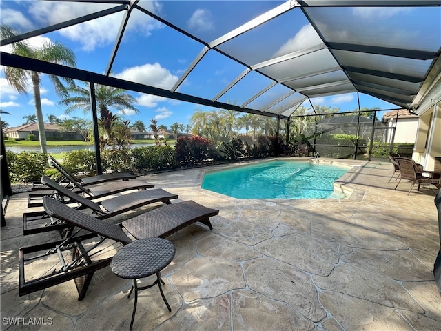 view of pool with glass enclosure, a patio area, and a water view