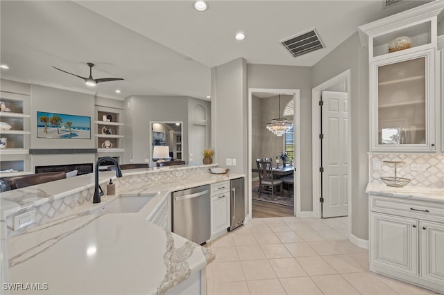 kitchen with stainless steel dishwasher, ceiling fan, light tile patterned floors, a fireplace, and white cabinetry