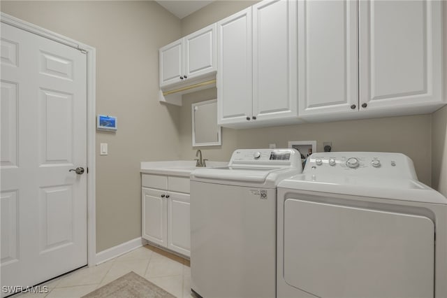 washroom with cabinets, washing machine and dryer, light tile patterned floors, and sink