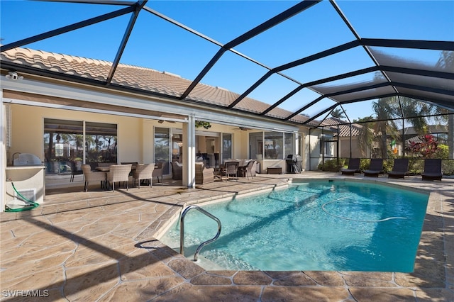 view of pool with glass enclosure, ceiling fan, and a patio area