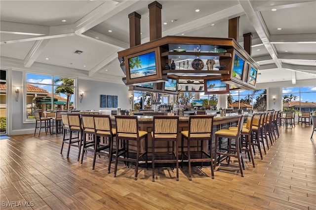 bar with light hardwood / wood-style flooring, beamed ceiling, and plenty of natural light