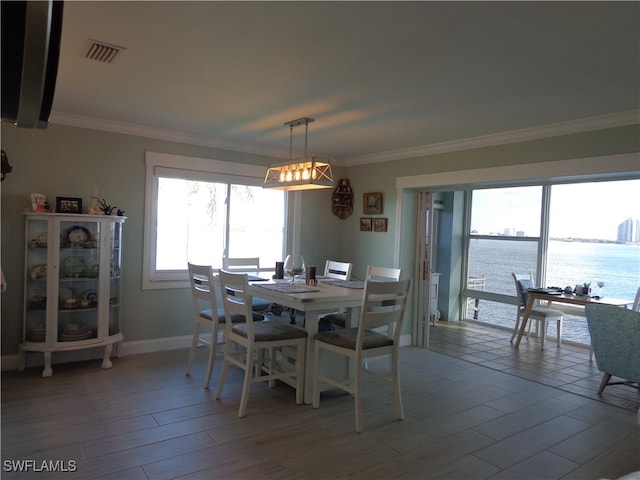 dining area with ornamental molding, hardwood / wood-style floors, and a water view