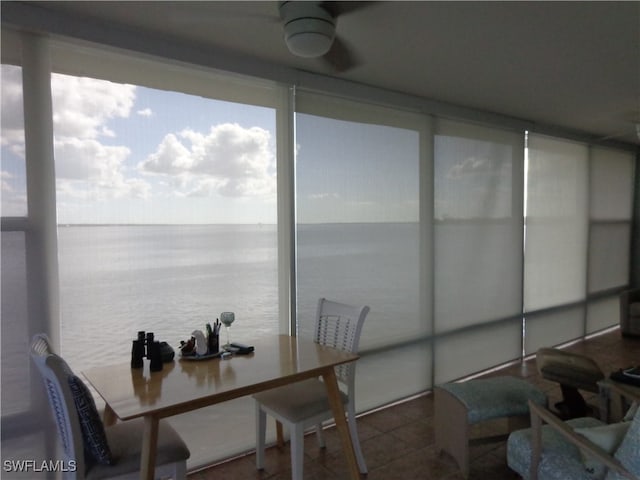 sunroom featuring a water view and ceiling fan