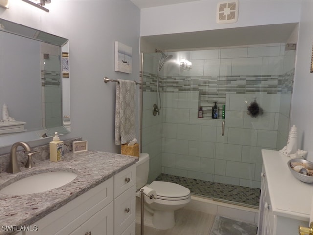 bathroom with toilet, a shower with shower door, and vanity