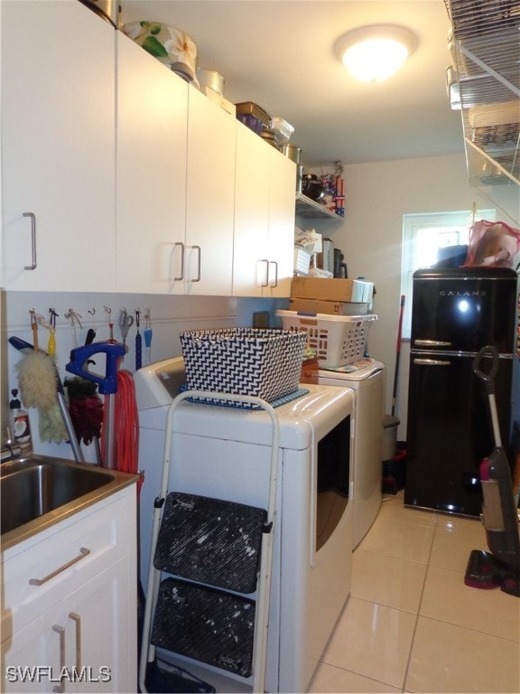 laundry area with cabinets, sink, washing machine and clothes dryer, and light tile patterned floors