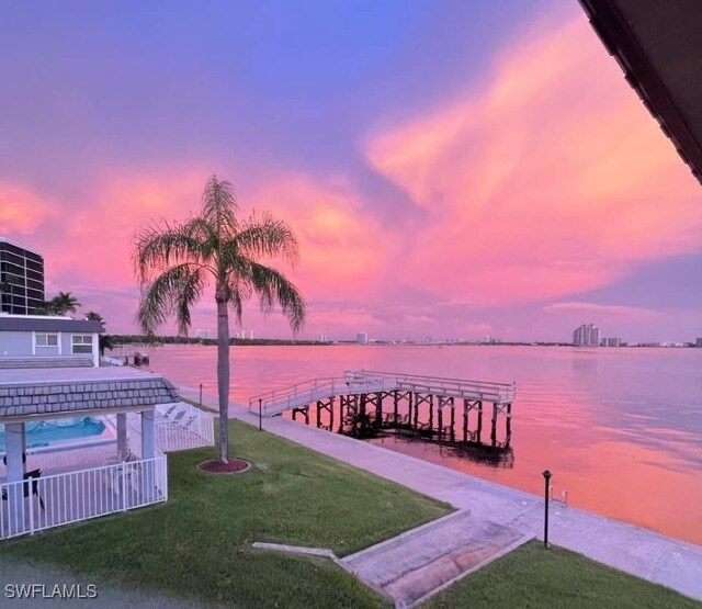 view of dock with a yard and a water view