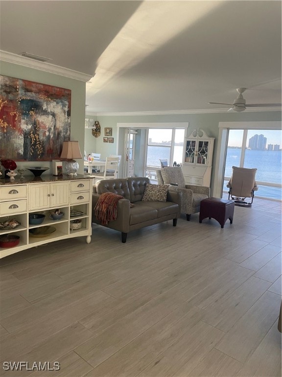 living room featuring crown molding, ceiling fan, wood-type flooring, and a wealth of natural light