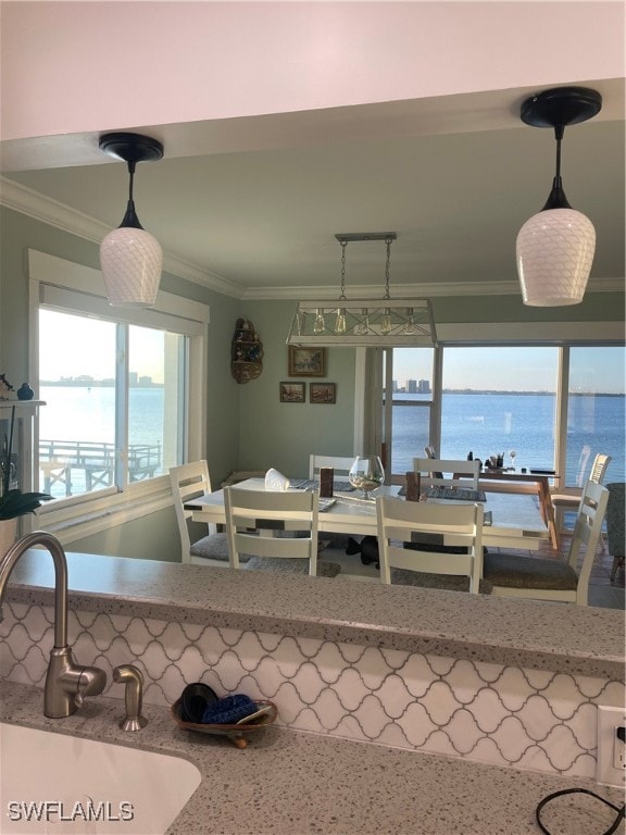 dining space featuring sink, crown molding, and a water view