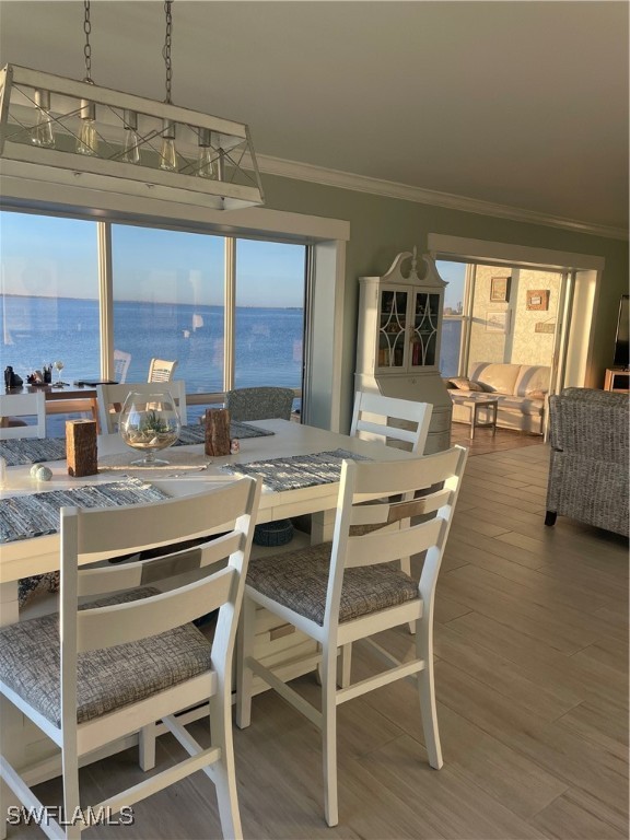 dining room featuring hardwood / wood-style floors, crown molding, and a water view