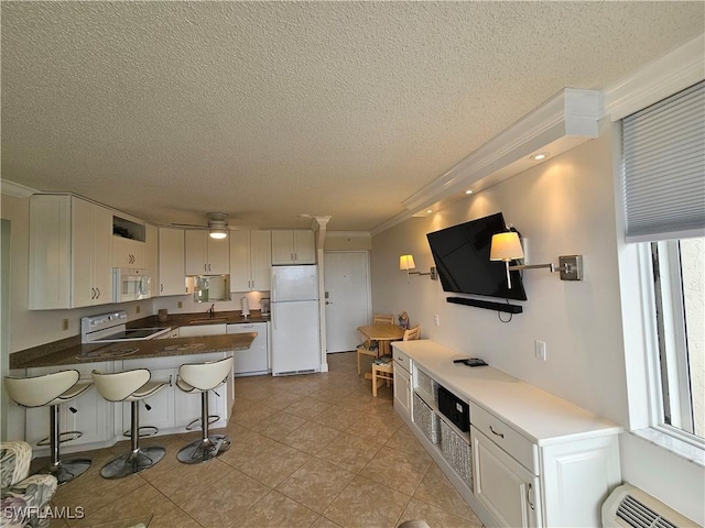 kitchen with a breakfast bar, white cabinetry, sink, ornamental molding, and white appliances