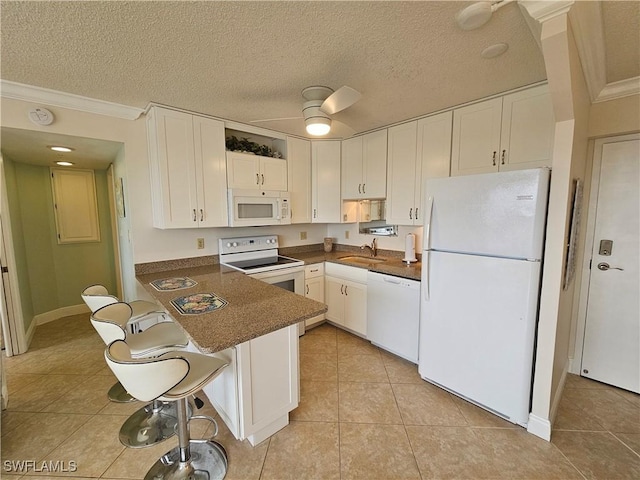 kitchen with white cabinetry, white appliances, a breakfast bar area, and kitchen peninsula