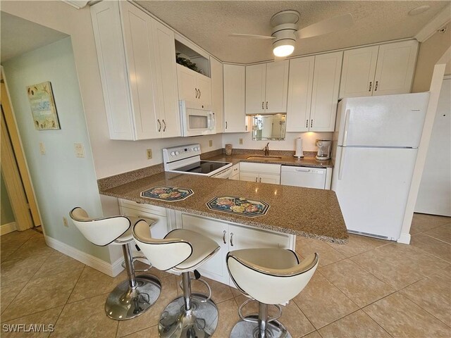 kitchen featuring a kitchen breakfast bar, white cabinetry, and white appliances