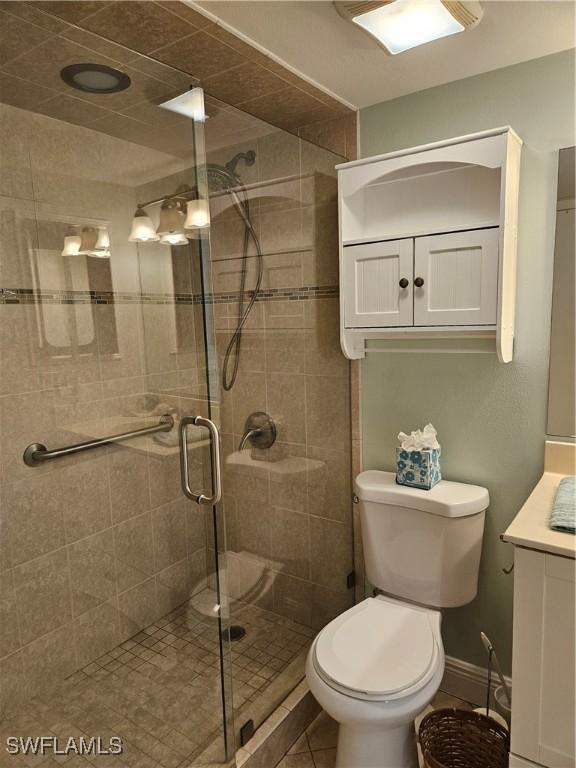 bathroom with walk in shower, vanity, and toilet