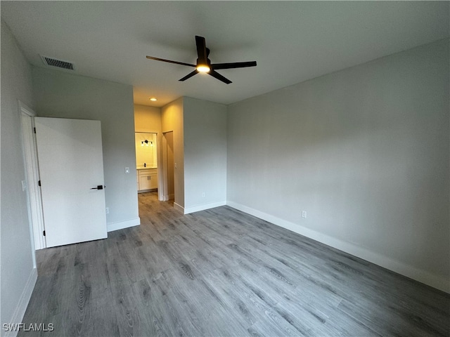 unfurnished bedroom featuring ceiling fan, ensuite bathroom, and wood-type flooring