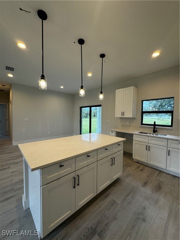 kitchen featuring hardwood / wood-style floors, sink, white cabinetry, and hanging light fixtures