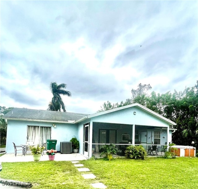 rear view of property featuring central air condition unit, a sunroom, a lawn, and a patio area