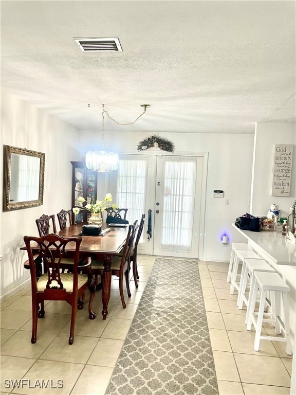 tiled dining space featuring a notable chandelier and a textured ceiling