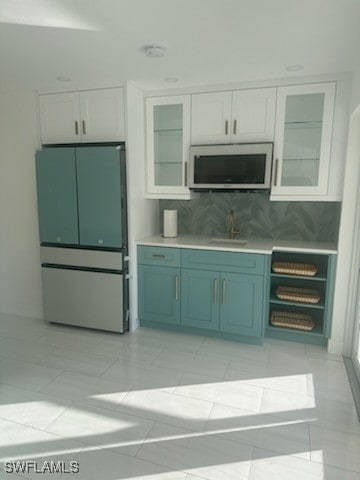 kitchen featuring white cabinets, green cabinets, light tile patterned floors, appliances with stainless steel finishes, and tasteful backsplash