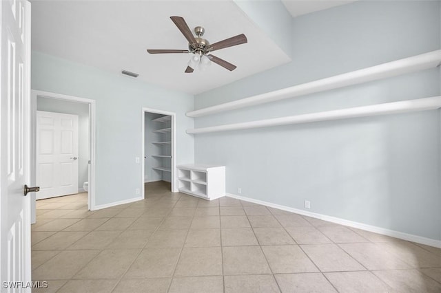 interior space featuring a spacious closet, ceiling fan, light tile patterned flooring, and a closet