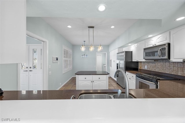 kitchen featuring backsplash, white cabinetry, stainless steel appliances, and hanging light fixtures