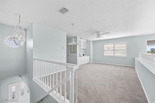 corridor featuring an inviting chandelier and light colored carpet