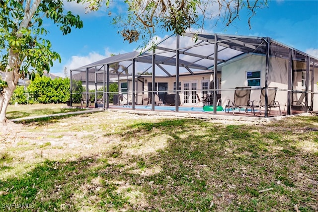 rear view of property with french doors, a patio area, glass enclosure, and a lawn