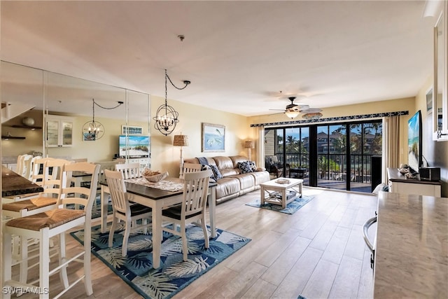 dining space with ceiling fan with notable chandelier and light wood-type flooring