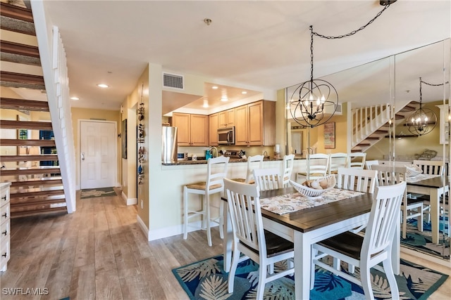 dining space with a notable chandelier and light wood-type flooring