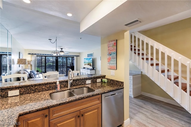 kitchen featuring stainless steel dishwasher, dark stone countertops, sink, and light hardwood / wood-style floors