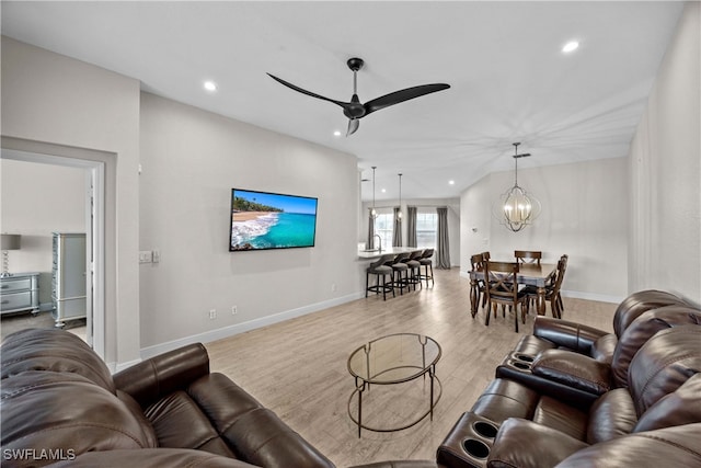 living room with light hardwood / wood-style floors and ceiling fan with notable chandelier