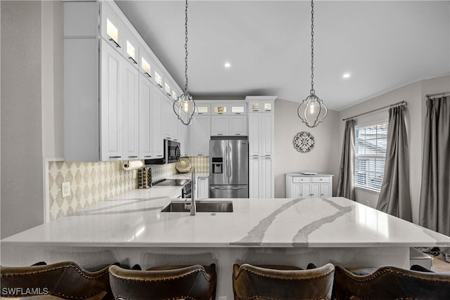 kitchen with decorative backsplash, a kitchen breakfast bar, hanging light fixtures, stainless steel appliances, and kitchen peninsula