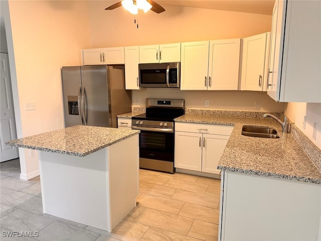 kitchen with lofted ceiling, white cabinets, appliances with stainless steel finishes, sink, and a center island