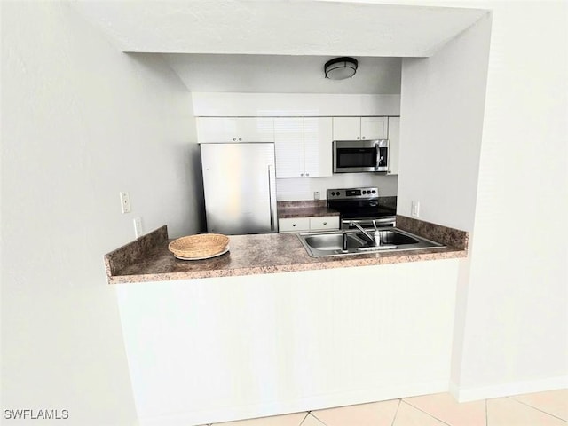 kitchen with light tile patterned floors, appliances with stainless steel finishes, sink, and white cabinets