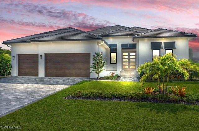 view of front of home with french doors, a lawn, and a garage