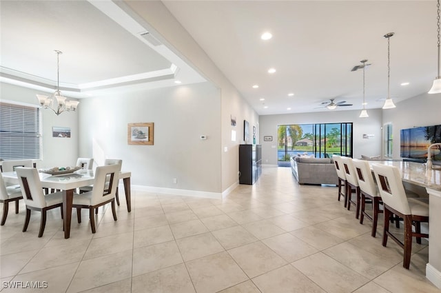 tiled dining room featuring a raised ceiling and ceiling fan with notable chandelier